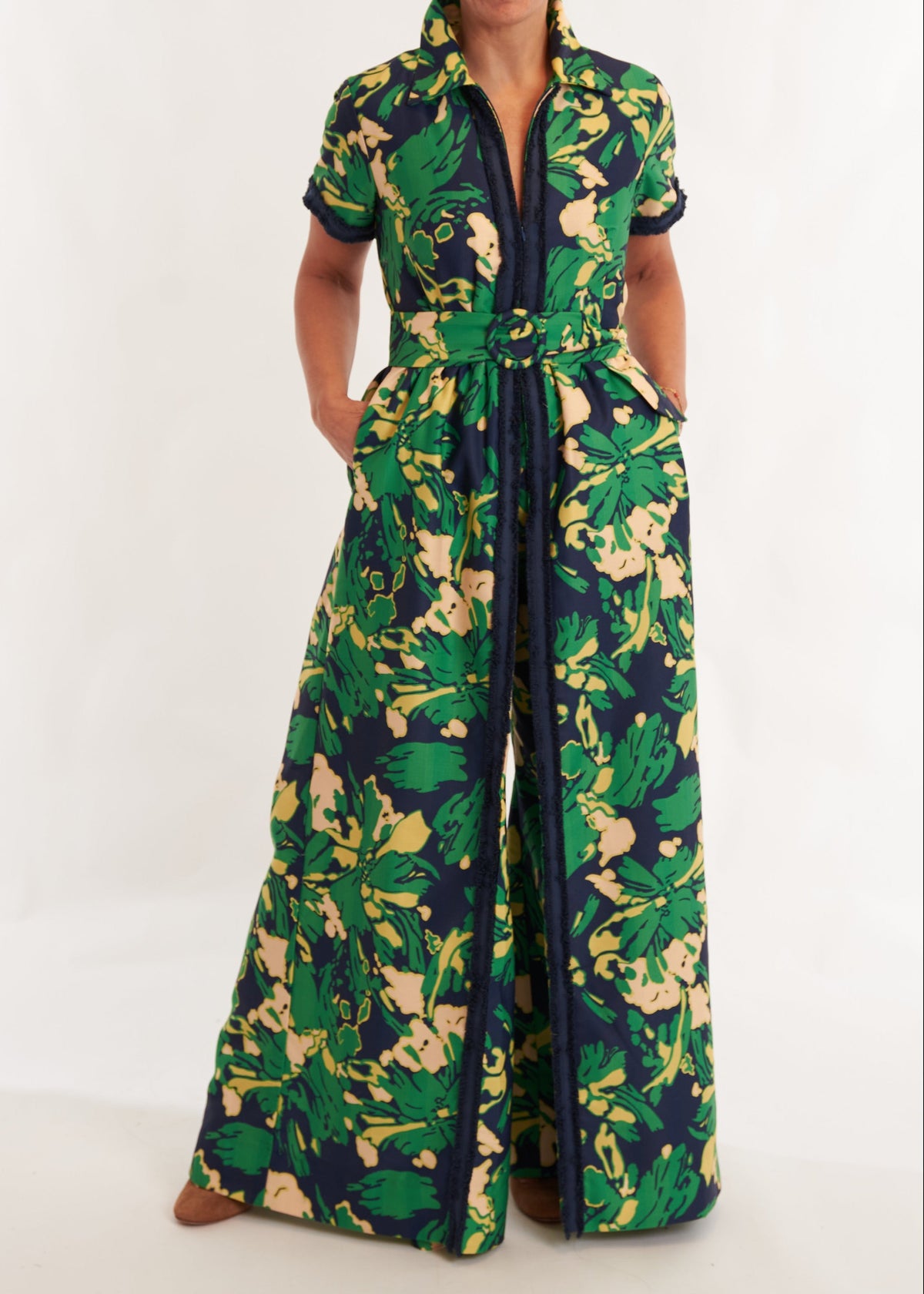 Person wearing a green and yellow floral jumpsuit on a white background