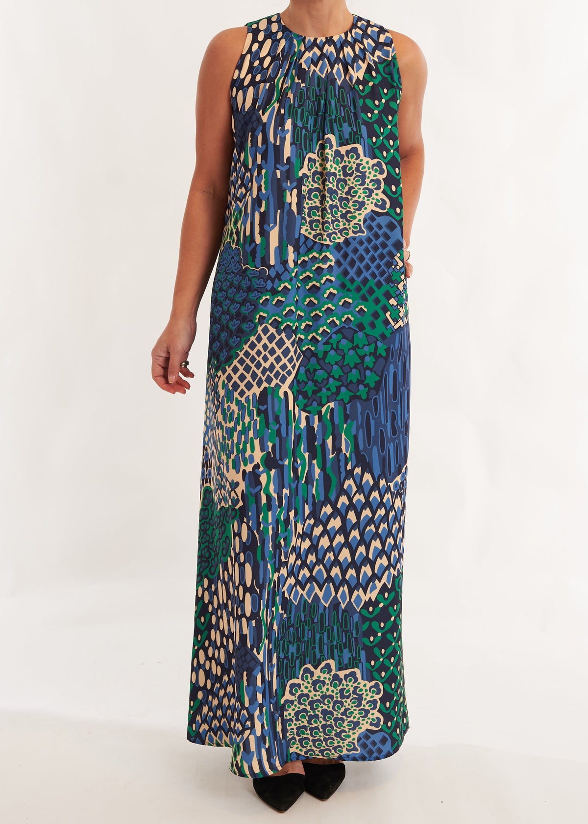 Woman wearing a sleeveless, long, patterned dress on a white background